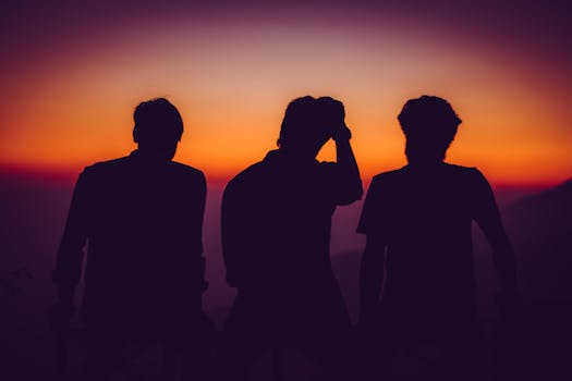 Silhouetted figures of three men captured during a vivid sunset with colorful sky.